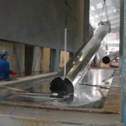 Гаряче цинкування на заводі та люди в робочій формі, які піднімають трубу-galery